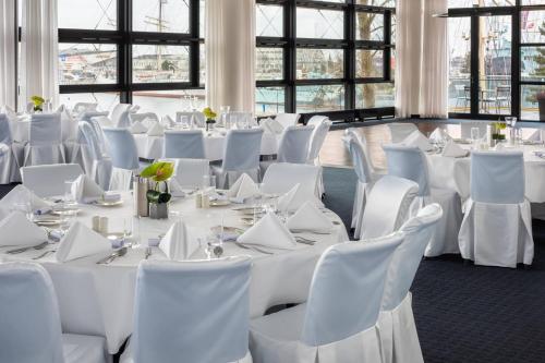 a room filled with white tables and white chairs at Courtyard by Marriott Gdynia Waterfront in Gdynia
