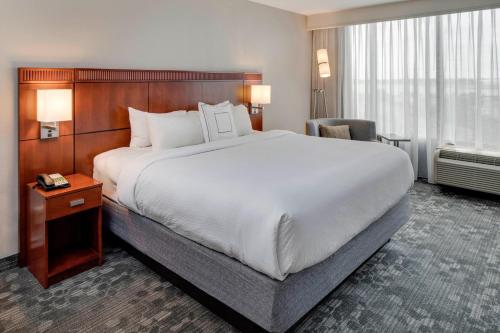 a hotel room with a large bed and a chair at Courtyard by Marriott Boston Logan Airport in Boston