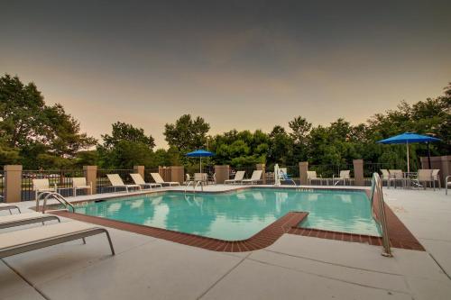a large swimming pool with chairs and umbrellas at Holiday Inn Express Voorhees/ Mt. Laurel by IHG in Voorhees