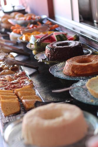 a table filled with different types of cakes and pastries at Pousada Semente in Arraial d'Ajuda