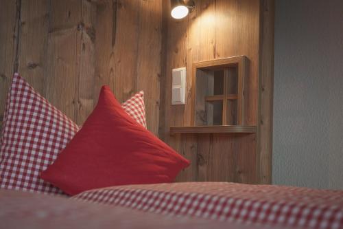 a bedroom with red pillows and a wooden wall at B&B Talstation Ferienwohnung für 2 Personen in Hörselberg-Hainich