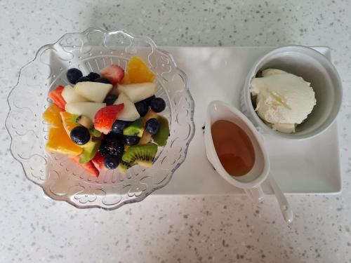 a bowl of fruit and a bowl of ice cream and a cup of sauce at Brookside Guest House & Mini Spa in Brixham