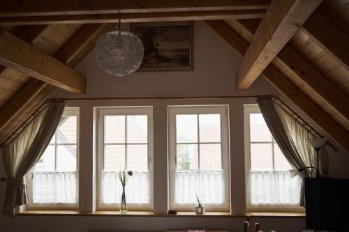 a room with three windows and a chandelier at B&B Talstation Ferienwohnung für 2 Personen in Hörselberg-Hainich