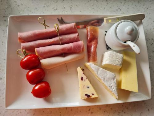 a plate of food with meats and cheese and tomatoes at Brookside Guest House & Mini Spa in Brixham