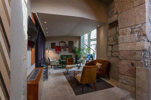 a living room with a stone wall and a table and chairs at Pestana Vintage Porto Hotel & World Heritage Site in Porto