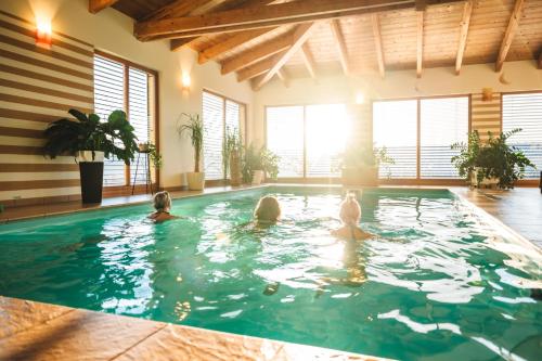 a group of three people swimming in a swimming pool at Wellness Pension Waldhof in Sankt Georgen