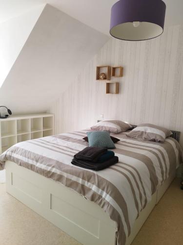 - une chambre avec un grand lit blanc et une lampe violette dans l'établissement Comme à la maison, à Cherbourg en Cotentin