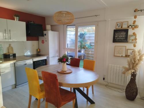 - une cuisine avec une table en bois, des chaises et une table dans l'établissement Comme à la maison, à Cherbourg en Cotentin