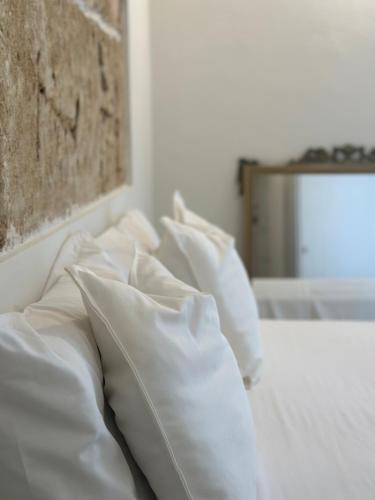 a pile of white pillows on a bed at F Home in Noto
