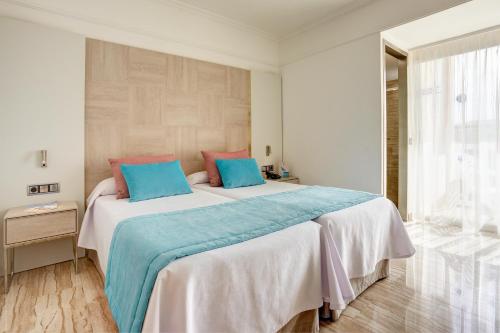 ein Schlafzimmer mit einem großen Bett mit blauen und rosa Kissen in der Unterkunft Grupotel Orient in Playa de Palma