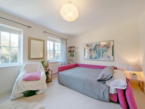 1 dormitorio con 1 cama rosa y 2 sillas en Wealden House - Westhampnett, en Westhampnett