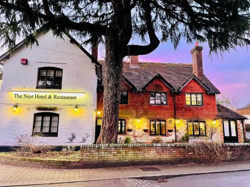 a white and red house with a tree in front of it at The Nest Hotel & Restaurant in Petersfield