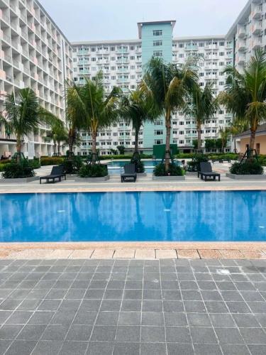 a swimming pool with palm trees in front of a building at Filed Residences Hotel Apartment in Manila