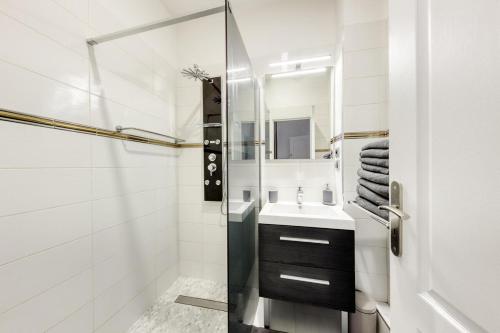 ein weißes Badezimmer mit Waschbecken und Spiegel in der Unterkunft Arc & Luxe Champs-Elysées in Paris