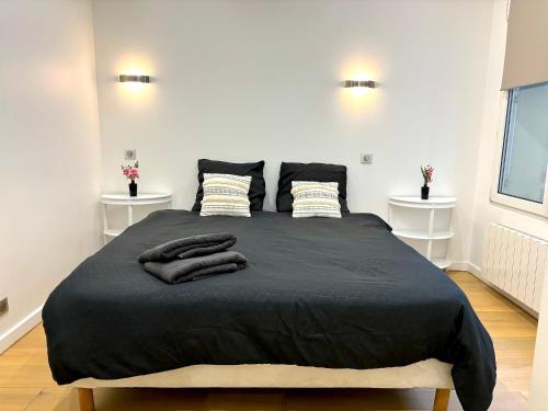 - une chambre avec un lit noir et 2 oreillers dans l'établissement L'appartement Murat, à Paris