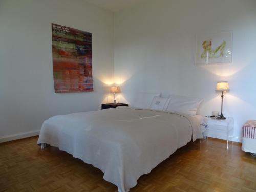 a white bedroom with a white bed and two lamps at The Garden Guesthouse in Basel