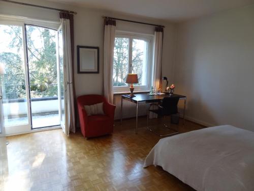 a bedroom with a bed and a table and a chair at The Garden Guesthouse in Basel