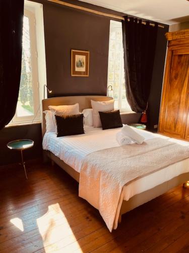 une chambre avec un grand lit avec des draps et des oreillers blancs dans l'établissement Le Manoir du Thouron, à Saint-Sulpice