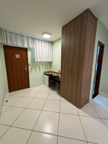 an empty room with a table and a wooden cabinet at Domus Hotel Veneza - Ipatinga in Ipatinga