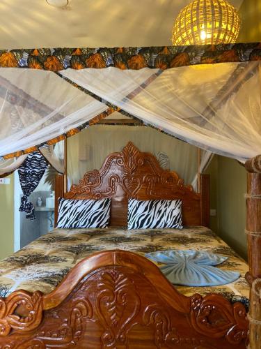 a bedroom with a wooden bed with a canopy at Bougainvillea nungwi zanzibar in Nungwi