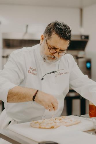 a man in a kitchen preparing a pizza at Domaine Des Hautes Fagnes in Ovifat