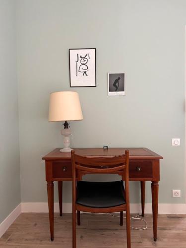a wooden desk with a lamp and a chair at La Maison d'Armand in Doudeville