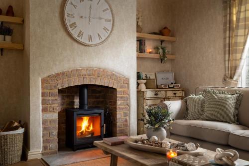 a living room with a fireplace and a clock on the wall at Broadway Country Chic Cottage in Broadway
