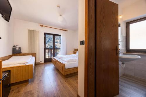 a room with two beds and a sink and a bathroom at Hotel Bellamonte in Predazzo