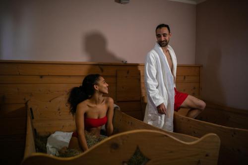 a man and a woman are standing in beds at Hotel Bellamonte in Predazzo