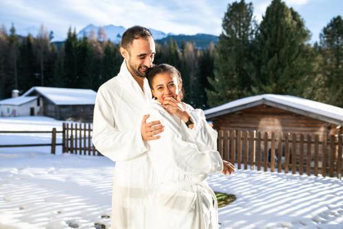 a man and woman dressed in white in the snow at Hotel Bellamonte in Predazzo