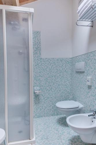 a bathroom with a shower and a toilet and a sink at Hotel Bellamonte in Predazzo
