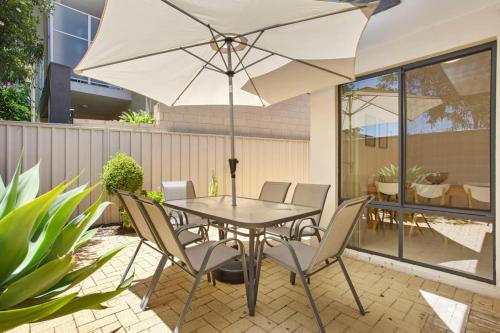 a table with chairs and an umbrella on a patio at Beachside Gem in Doubleview, Free Wi-Fi, Parking in Perth