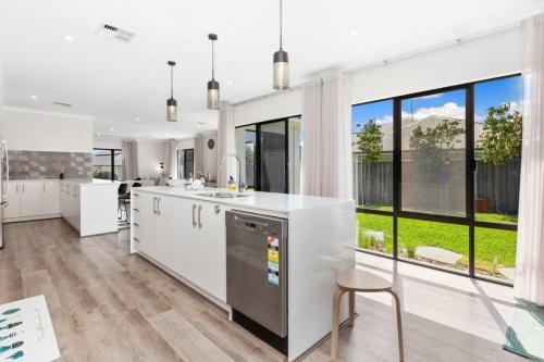 a kitchen with white cabinets and a large window at A wonderful life in the heart of Treeby in Perth