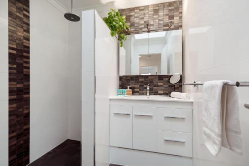 a white bathroom with a sink and a mirror at The Little Peaceful Retreat, 600m to Scarb Beach in Perth