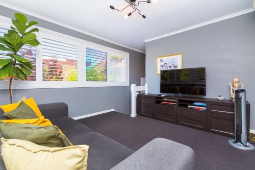 a living room with a couch and a flat screen tv at Fusion of 20th century charm and modern convenience in Perth