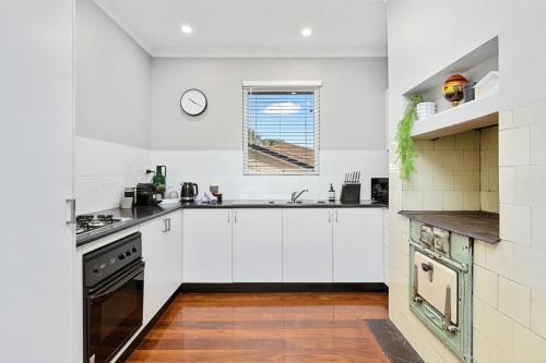 a kitchen with white cabinets and a window at Sasha's Cottage on the Hill BBQ & Entertainment in Perth