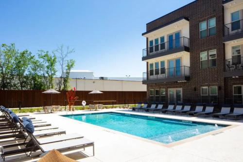 a swimming pool with chairs and a building at Serene Escape 1BD Pool 2 min to TCU in Fort Worth