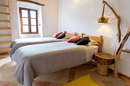 two beds sitting in a room with at Quinta do Arade - casa 4 pétalas in Barranco do Resgalho