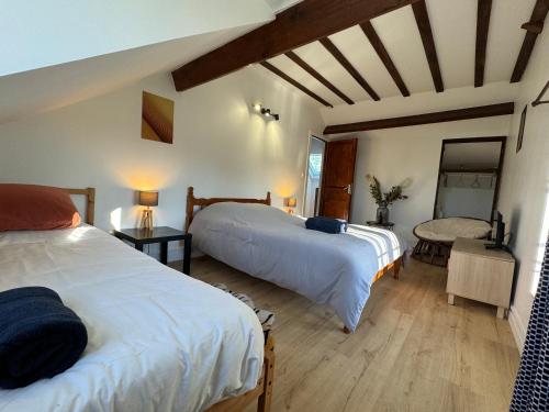 a bedroom with two beds and a table with a mirror at La Chaumière du bout du chemin - 7p - Ch RDC in Neuville-sur-Touques