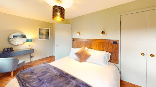 a bedroom with a white bed and a chair at Fraser Cottage in Kincraig