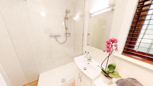 a white bathroom with a sink and a shower at Fraser Cottage in Kincraig