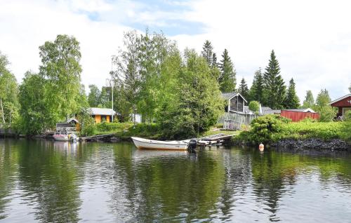 a boat is docked on a river next to houses at 3 Bedroom Beautiful Home In Umeå in Umeå