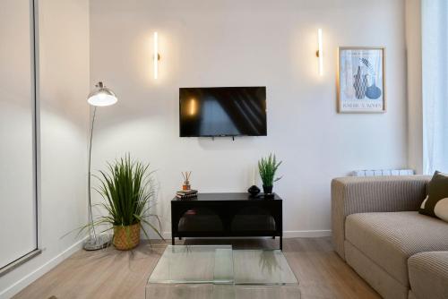 un salon avec un canapé et une télévision sur un mur dans l'établissement Appartement deux chambres & deux salles de bain, à Villeneuve d'Ascq