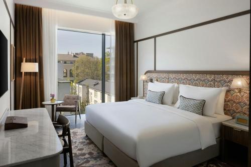 a hotel room with a large white bed and a window at Stradom House, Autograph Collection in Kraków
