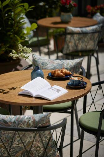 a table with an open book and a plate of food at Stradom House, Autograph Collection in Kraków