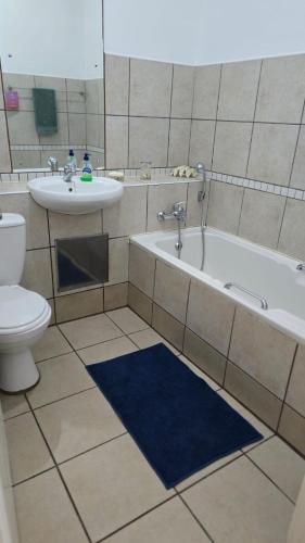 a bathroom with a tub and a sink and a toilet at 407 L'Escalier Cabanas -Beachfront Paradise in Amanzimtoti