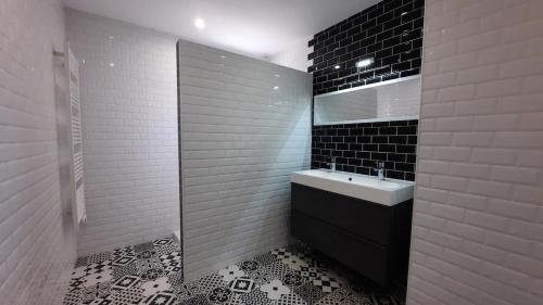 La salle de bains est pourvue d'un lavabo et de carrelage noir et blanc. dans l'établissement Pavillon individuel plain-pied avec terrasse et parking, à Saint-Vigor-le-Grand