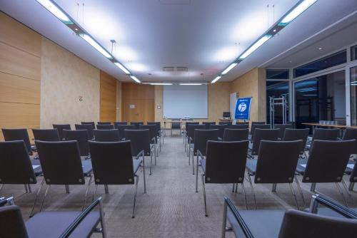 a room with rows of chairs and a screen at Fletcher Waldhotel Nordrhein-Westfalen in Heiligenhaus