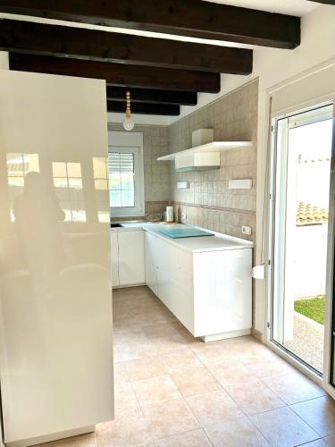 a kitchen with white cabinets and a large window at Ca' na Cocca - Chalet con piscina privata in Cala en Bosc