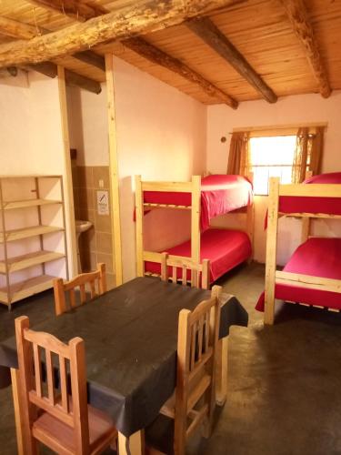 ロデオにあるCabañas Zorzal Rodeoのテーブル、椅子、二段ベッドが備わる客室です。